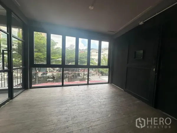 Retail Space for rent - Corner room with floor-to-ceiling windows overlooking a tree-lined plaza near BTS Phra Khanong.