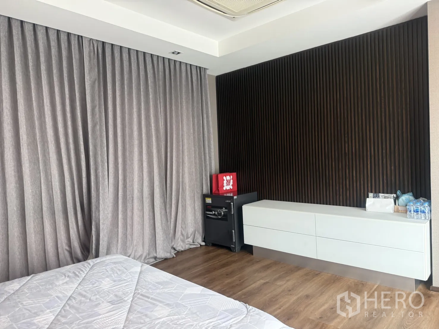 Detached House for rent in Bang Kapi, Bangkok - Bedroom view with dark slatted accent wall, low storage cabinet, and safe.