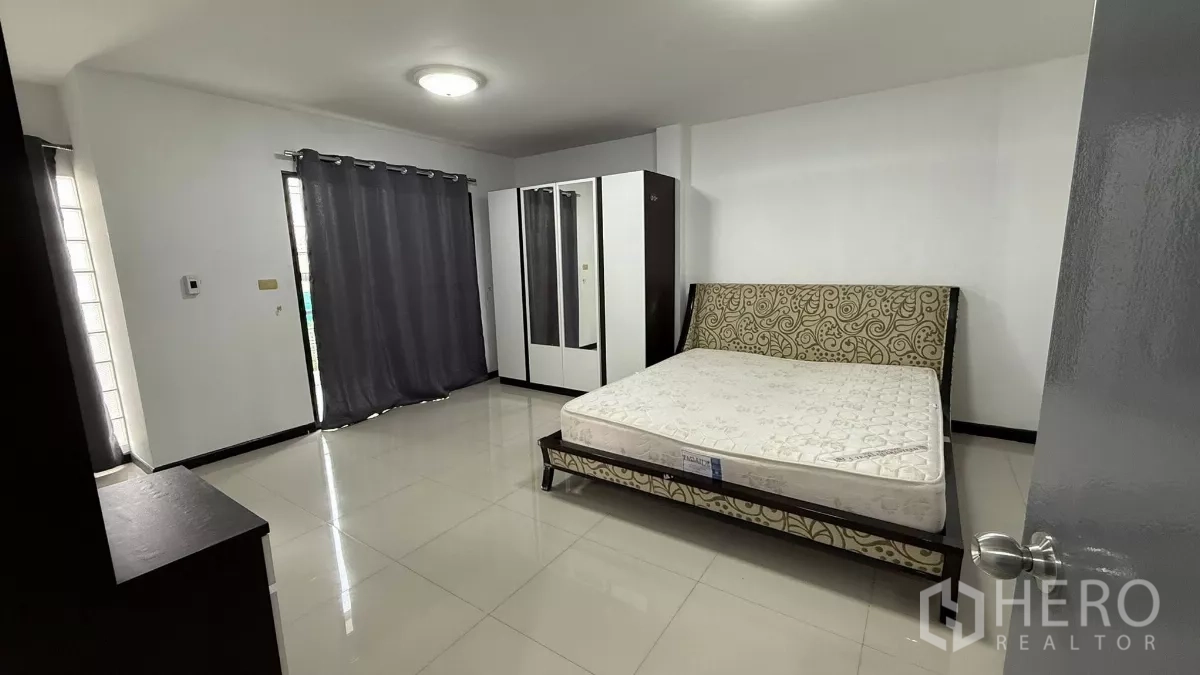 Home Office for rent in Bang Na, Bangkok - Large bedroom with patterned headboard, wardrobe, sliding door to balcony and blackout curtains.