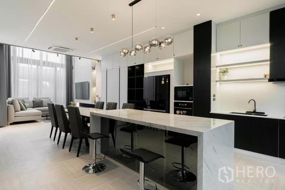 Townhouse for sale in Chatuchak, Bangkok - Open-plan kitchen and dining with long marble island and pendant lights.