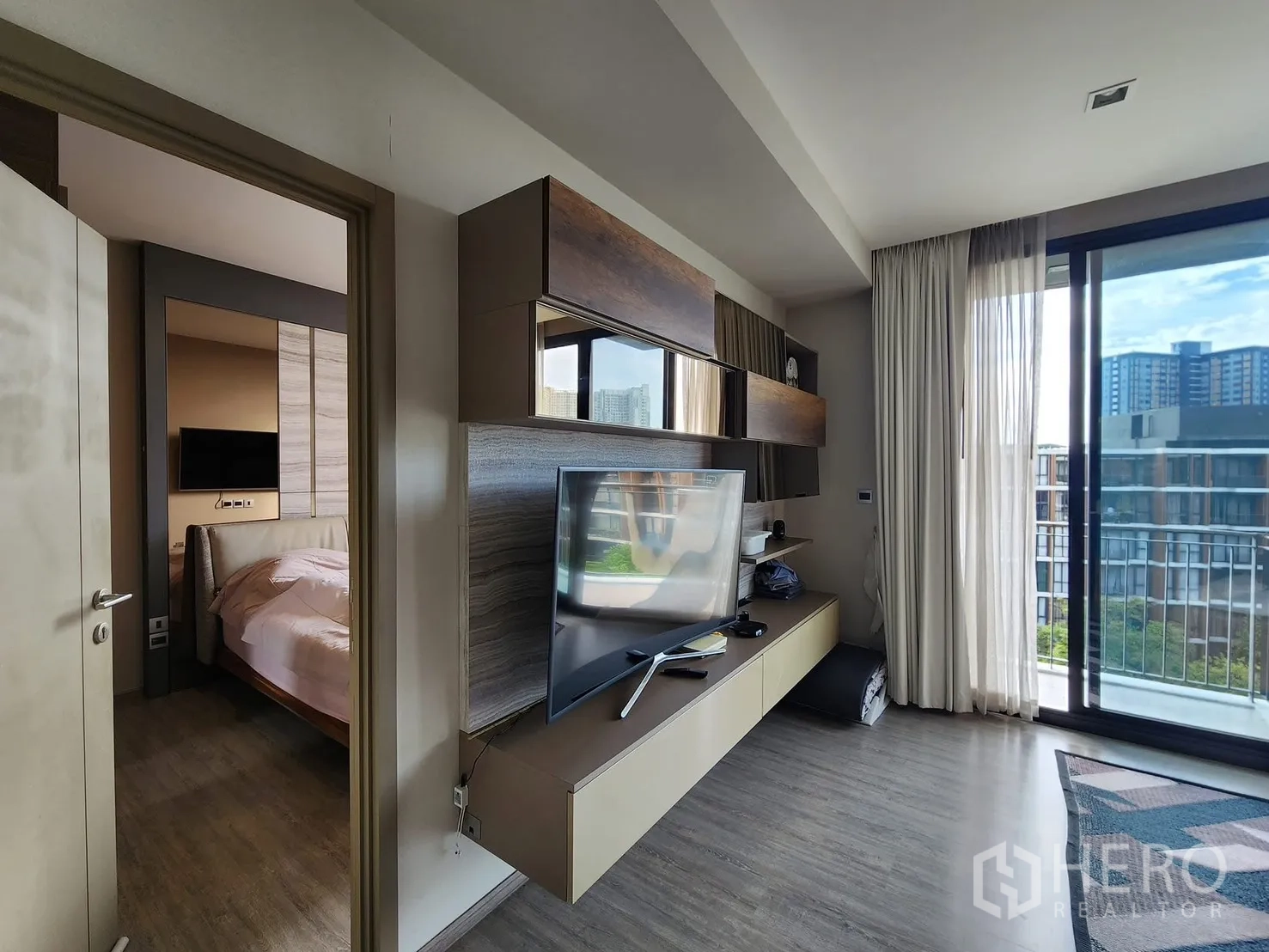 公寓 for rent in Watthana, Bangkok - 客厅电视墙与卧室门，旁为通往阳台的大型推拉门。