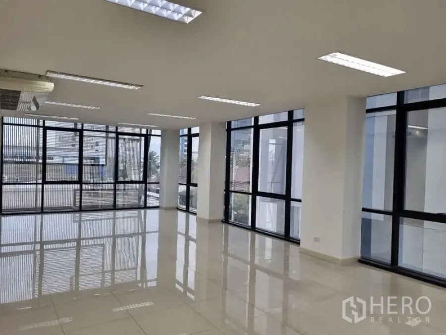 Office Space for rent in Bang Kho Laem, Bangkok - Bright empty corner office with large black-framed windows, glossy tile flooring and recessed ceiling lights.