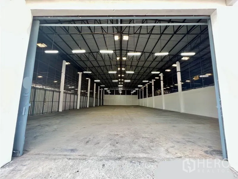 货栈 出租在Pak Kret, Nonthaburi - 仓库内部：高净高钢结构屋顶、LED照明、白色立柱与抛光混凝土地面。