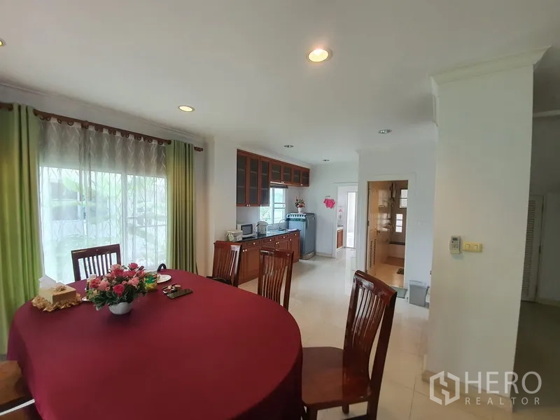 独立式住宅 出租在Lat Krabang, Bangkok - 开放式餐区，圆桌靠窗，旁连备餐台与绿色窗帘。