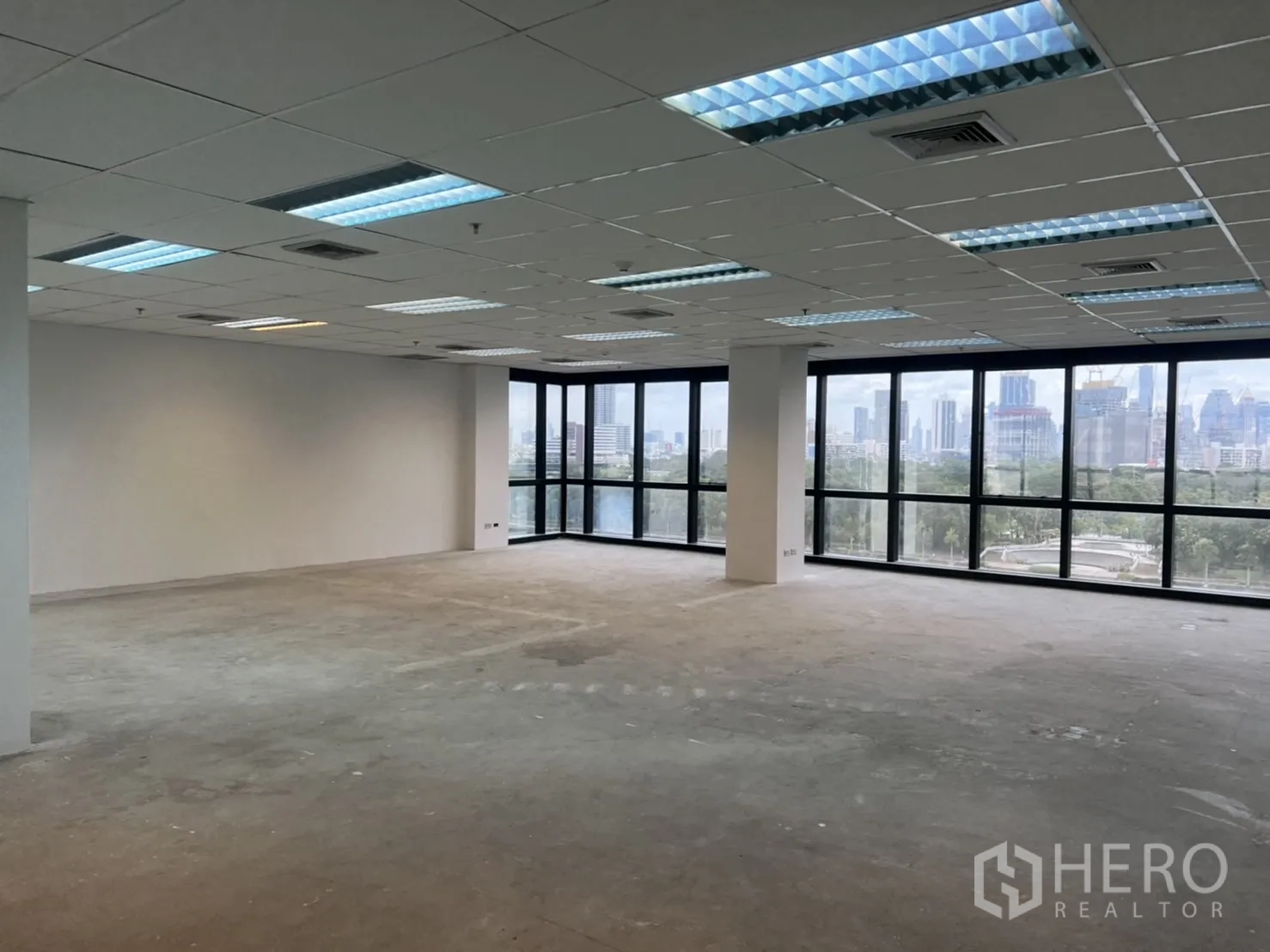 Office Space for rent in Watthana, Bangkok - Open-plan office with grid ceiling lights and broad windows facing the city and greenery.