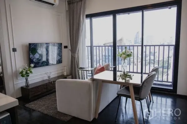 คอนโด ให้เช่าในWatthana, Bangkok - ห้องนั่งเล่นสว่าง โซฟา ทีวีติดผนัง ชุดทานข้าว และระเบียงวิวเมืองย่านทองหล่อ