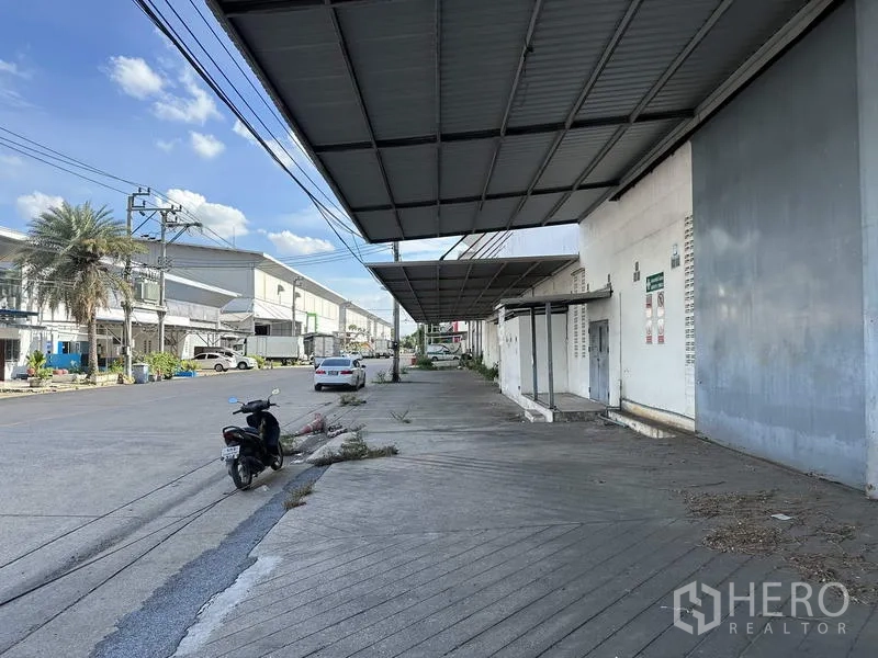 Factory for rent in Bang Bua Thong, Nonthaburi - Covered walkway and loading area facing a quiet industrial street with nearby units.