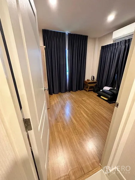 独立式住宅 出售在Prawet, Bangkok - 从门口望向卧室，木地板、深色窗帘与空调。