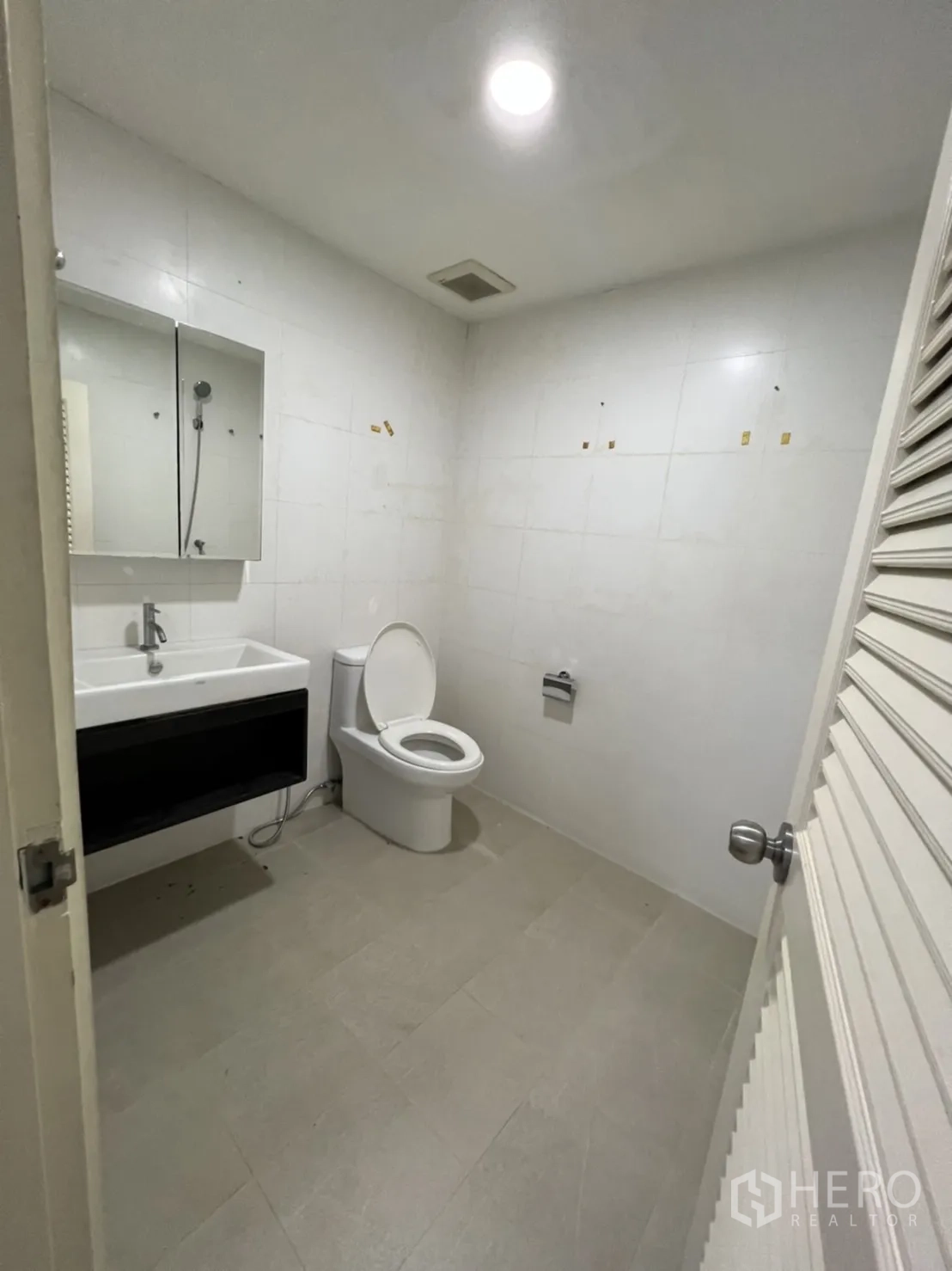 Shophouse for rent or sale in Watthana, Bangkok - Simple restroom with toilet, sink and wall mirror.