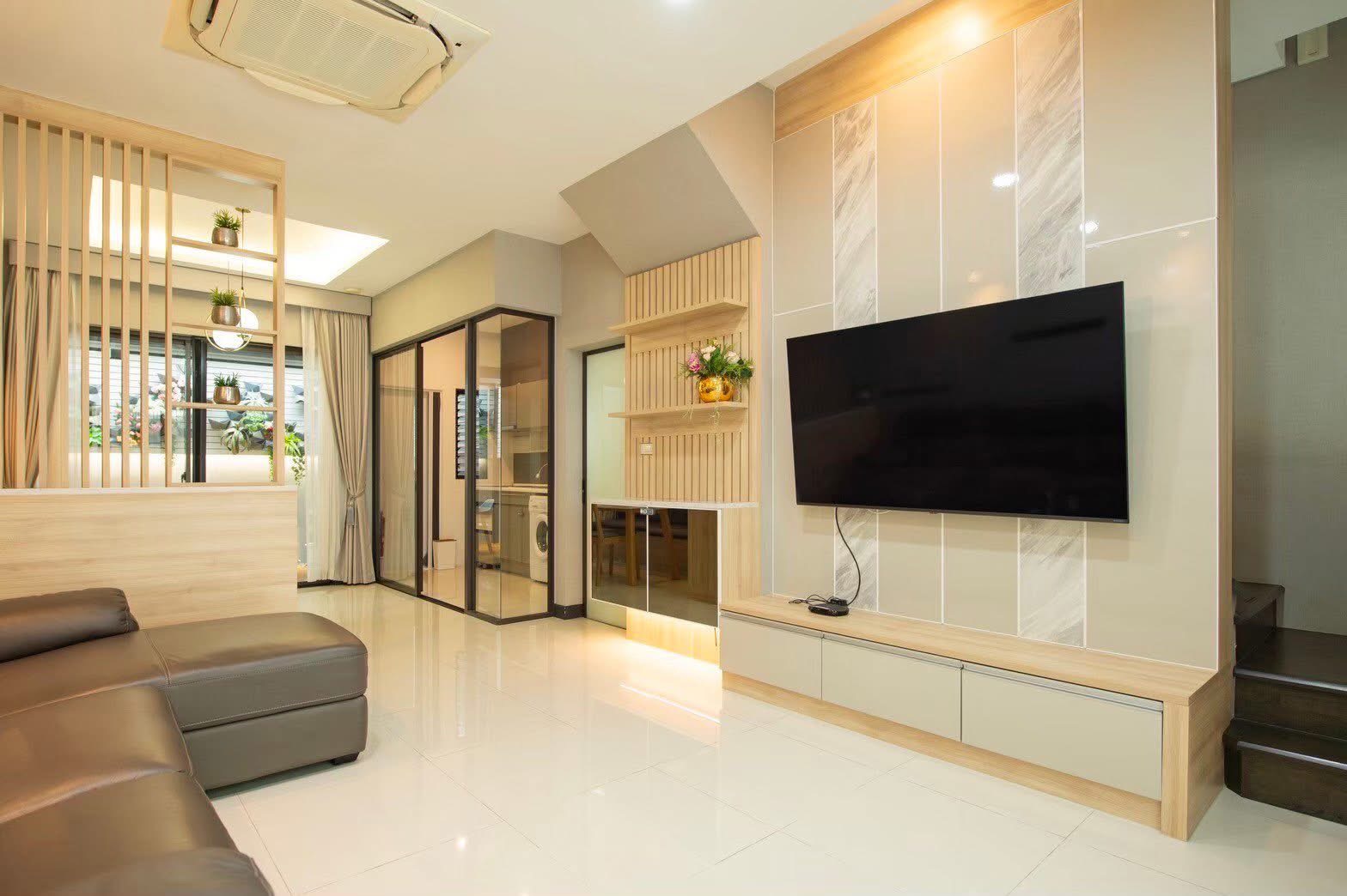 Townhouse for rent or sale in Lat Phrao, Bangkok - Bright lounge with big TV, glass-enclosed kitchen and an L-shaped sofa.