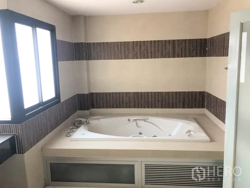 带办公室的家 出租在Wang Thonglang, Bangkok - 浴室内置按摩浴缸，条纹墙砖和磨砂采光窗。
