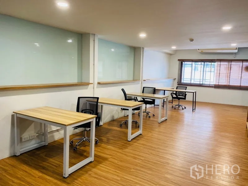 Office Space for rent in Bang Rak, Bangkok - Spacious open workspace with multiple desks, large window and wood flooring.