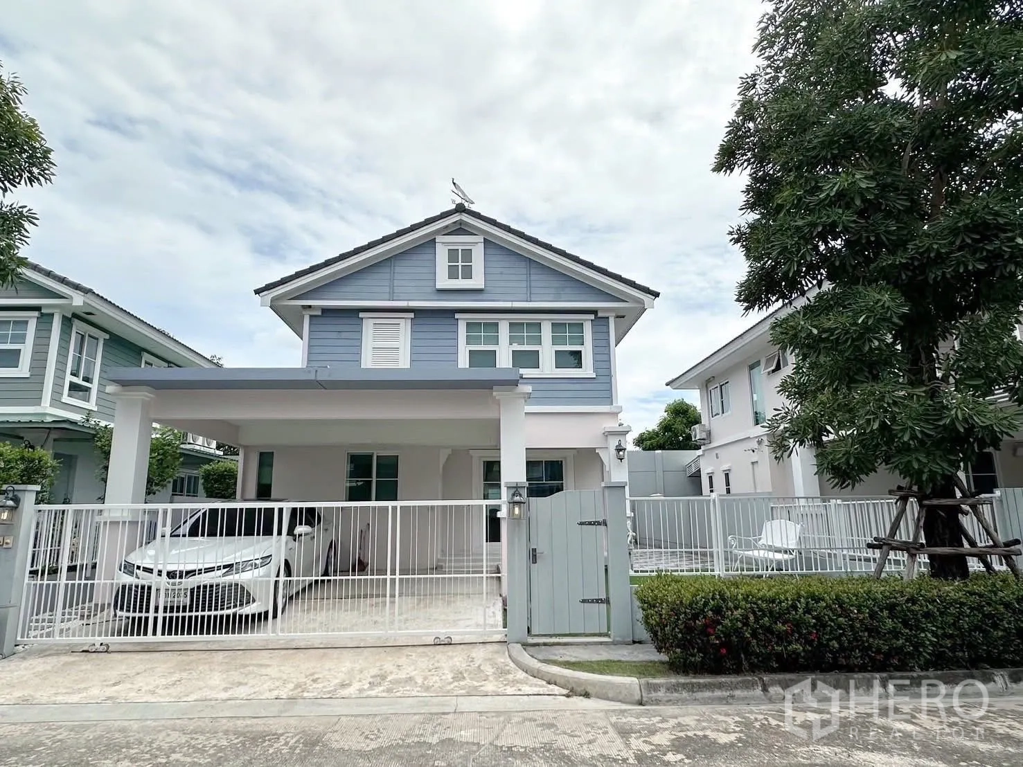 บ้าน ให้เช่าหรือขายในBang Phli, Samut Prakan - หน้าบ้านเดี่ยวสองชั้นโทนสีฟ้า มีรั้วและที่จอดรถในร่ม