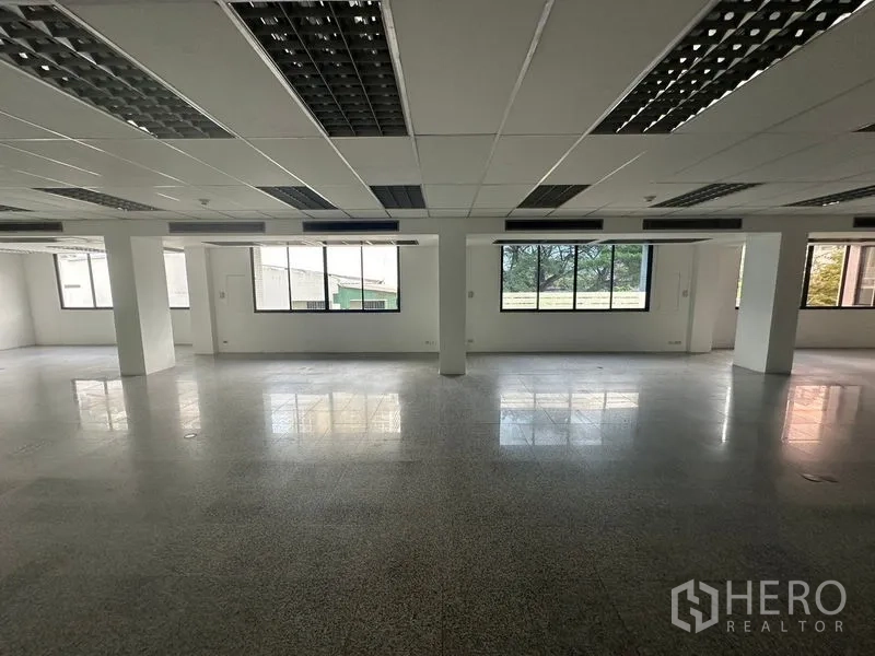 办公空间 出租 - 开放办公空间，窗外临绿色景观，带结构柱与抛光地面。