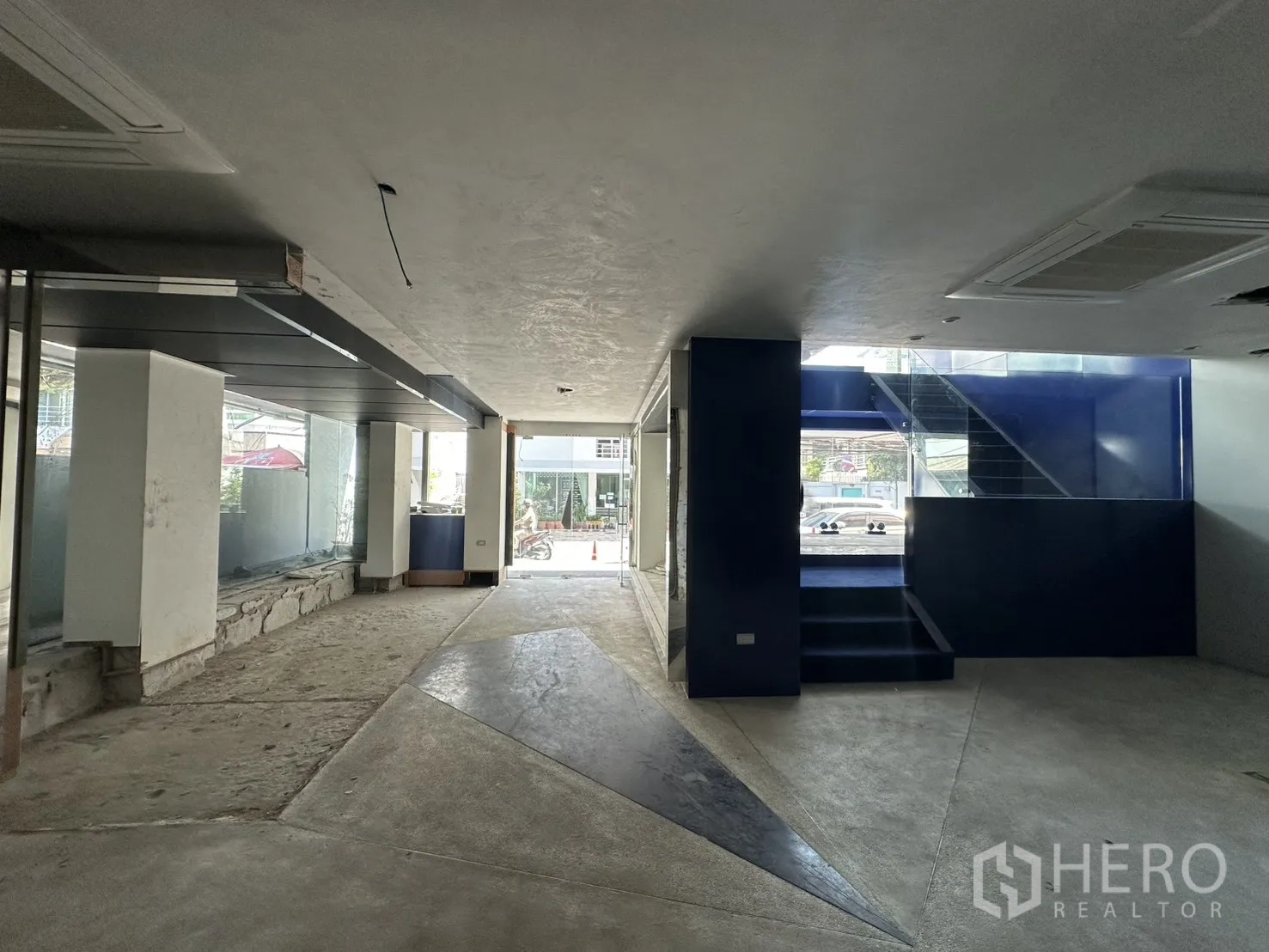 พื้นที่ขายของ for rent in Watthana, Bangkok - โถงลึกนำสายตาไปยังบันไดสีน้ำเงินและประตูกระจกหน้าอาคาร พื้นคอนกรีตและกระเบื้อง.
