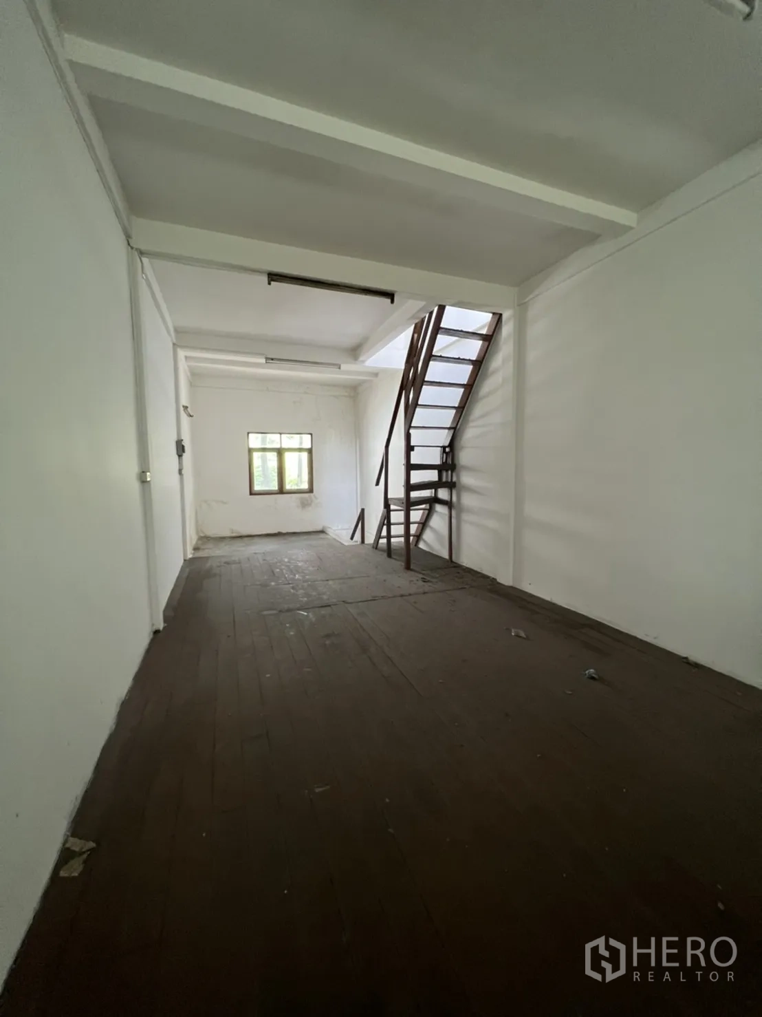 Shophouse for rent in Khlong Toei, Bangkok - Upper level room with dark wooden floor, white walls, small end window and an internal metal staircase.