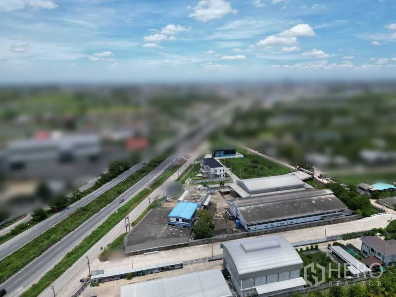 ที่ดิน ขายในBang Bua Thong, Nonthaburi - ภาพมุมสูงเห็นถนนสายหลักในพื้นที่ อาคารโรงงานหลังคาสีน้ำเงิน และทางเชื่อมรอบชนบท