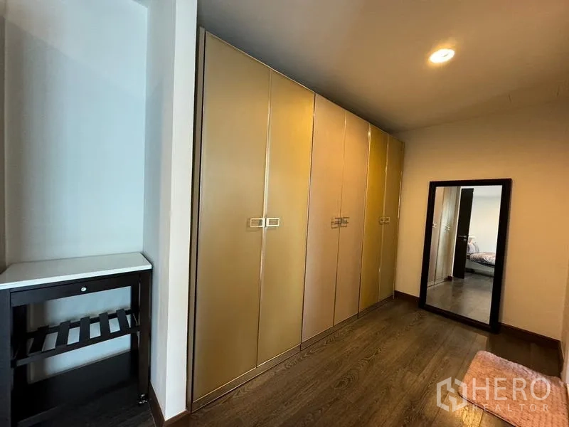 Condominium for rent in Pathum Wan, Bangkok - Dressing corridor with long built-in wardrobes and a standing mirror.