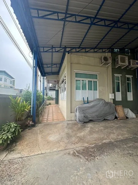Warehouse for rent or sale in Lam Luk Ka, Pathum Thani - Side elevation under canopy showing multiple air‑conditioners and access ramp.