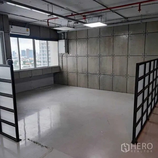 办公空间 出租在Watthana, Bangkok - 角落工作区，城市景观窗、混凝土板墙与空调。