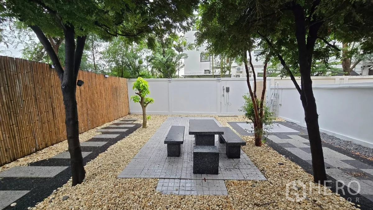 Townhouse for rent or sale in Saphan Sung, Bangkok - Landscaped backyard with stone patio, granite table set and pebble groundcover.