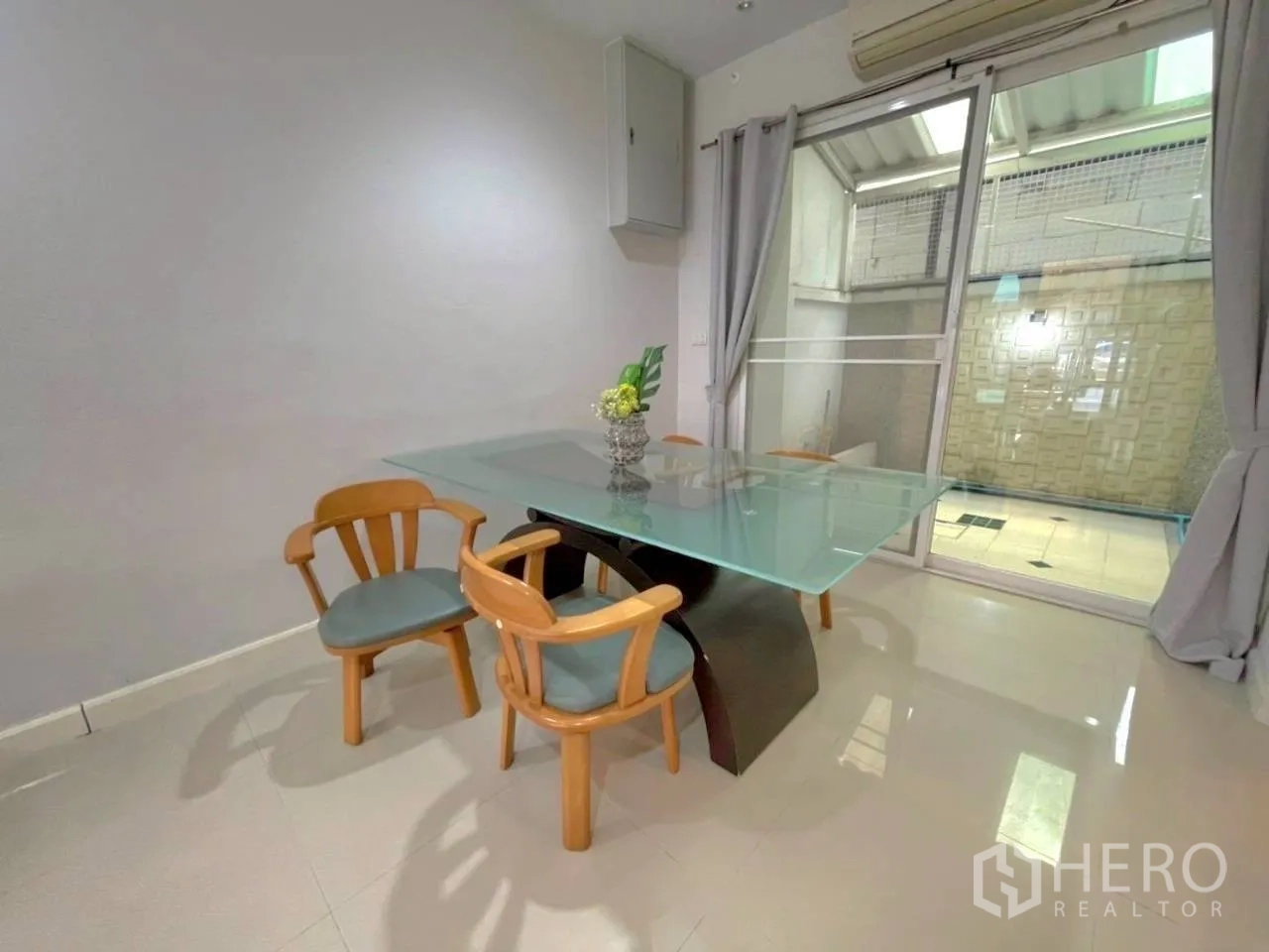 Townhouse for rent in Bang Kho Laem, Bangkok - Dining area with glass-top table and four chairs beside a sliding door to the patio.