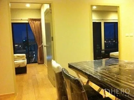 Condominium for rent in Watthana, Bangkok - Dining area with marble table leading to two bedrooms, with night city views through large windows.