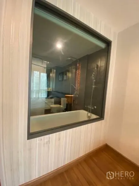 Condominium for rent in Watthana, Bangkok - Interior window looking into a bathroom with bathtub and glass-enclosed shower.