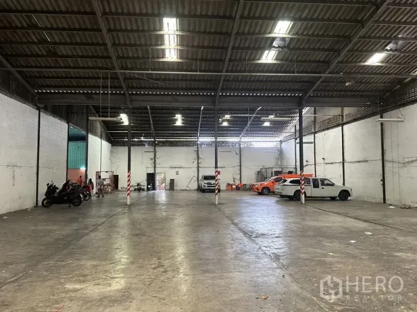 Warehouse for rent in Khan Na Yao, Bangkok - Open-plan warehouse floor with high clearance, white walls and parking for vehicles.