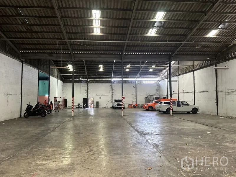 Warehouse for rent in Khan Na Yao, Bangkok - Open-plan warehouse floor with high clearance, white walls and parking for vehicles.