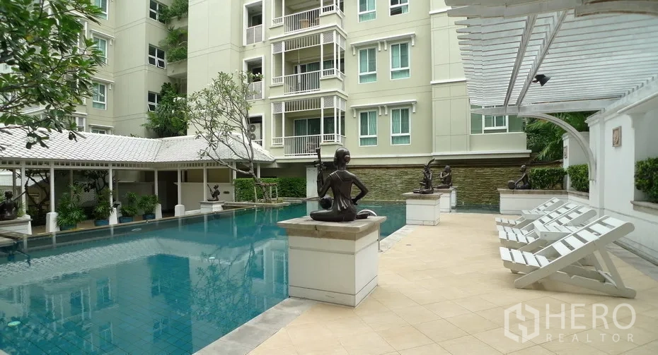 公寓 出租或出售在Watthana, Bangkok - 公寓户外泳池庭院，配躺椅、雕塑与绿化。