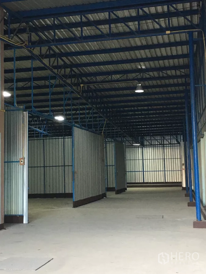Warehouse for rent in Bueng Kum, Bangkok - High-ceiling warehouse interior featuring steel trusses, hanging lights, and metal cladding.