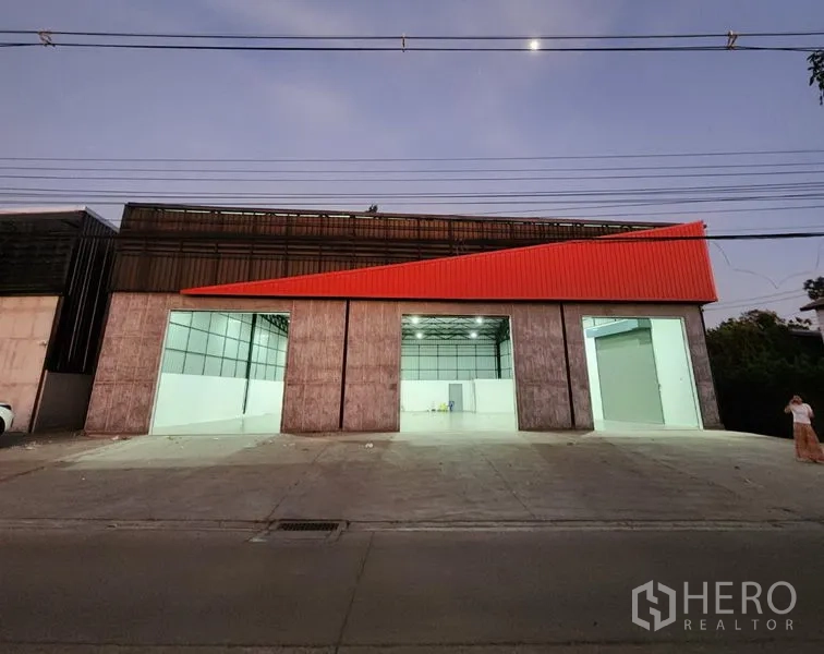 คลังสินค้า ให้เช่าในPak Kret, Nonthaburi - ภาพภายนอกช่วงค่ำ เปิดช่องทางขนถ่าย เผยให้เห็นภายในที่สว่างใต้อาคารหลังคาสูง