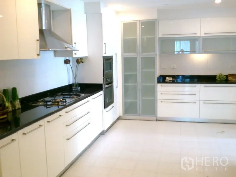 Condominium for rent in Khlong Toei, Bangkok - Full kitchen view with twin countertops, glass-front pantry and ample storage.