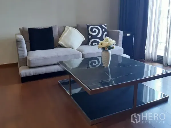 公寓 出租在Watthana, Bangkok - 现代客厅一角，灰色沙发与大理石面茶几、薄纱窗帘。
