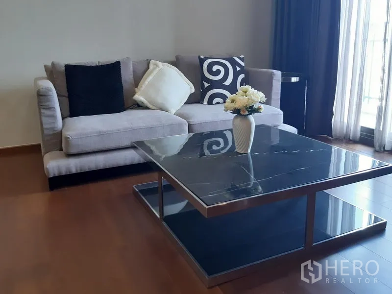 公寓 出租在Watthana, Bangkok - 现代客厅一角，灰色沙发与大理石面茶几、薄纱窗帘。
