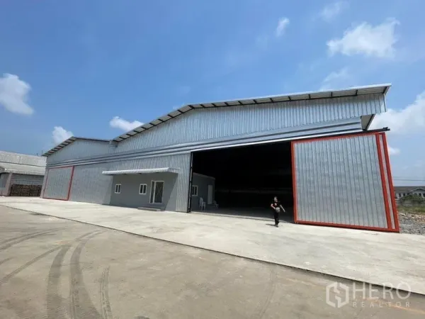 Factory for rent in Mueang Samut Sakhon, Samut Sakhon - Metal-clad factory with huge sliding doors and attached office, set on a wide concrete yard.