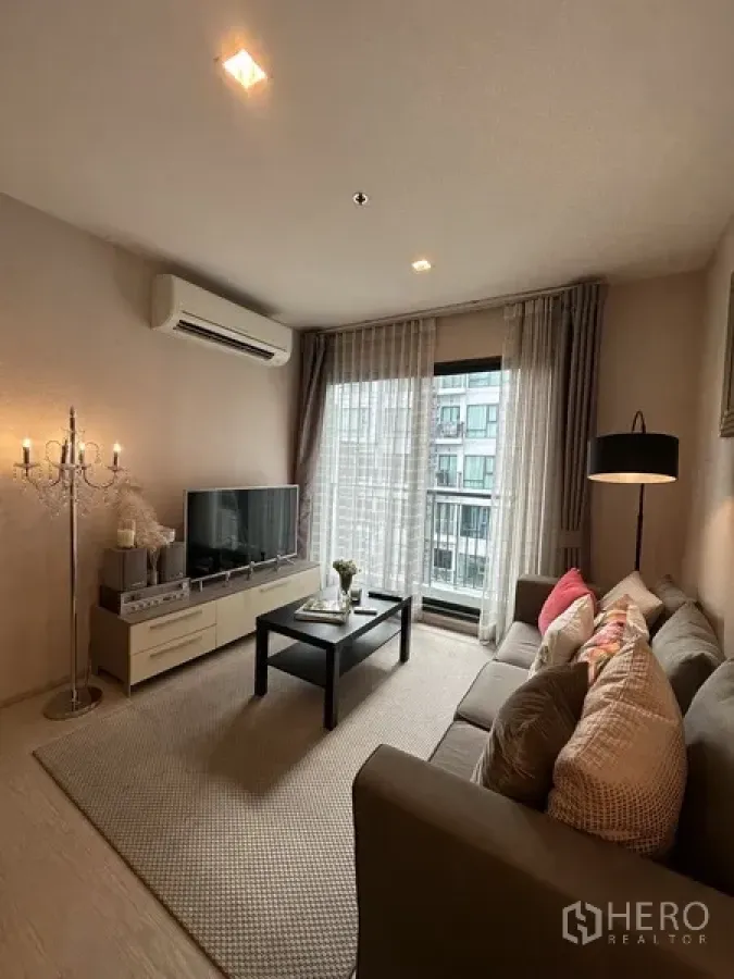 公寓 出租或出售在Khlong Toei, Bangkok - 客厅配电视、空调、茶几，并通向阳台的推拉门。
