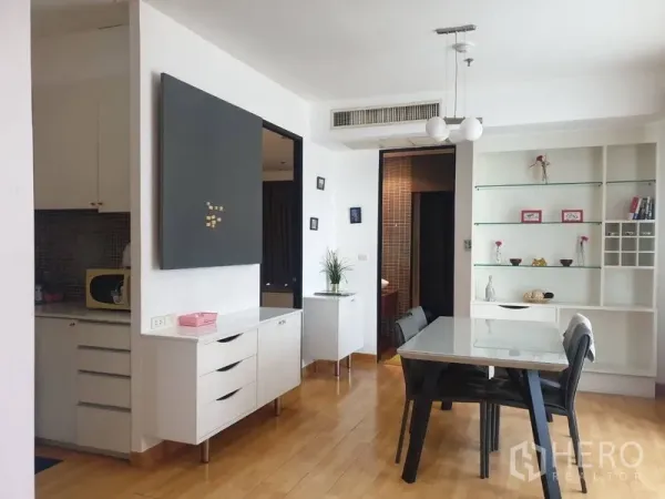 Condominium for rent in Khlong Toei, Bangkok - Bright dining area with built-in shelves, pendant lights, and wood floors beside the kitchen.