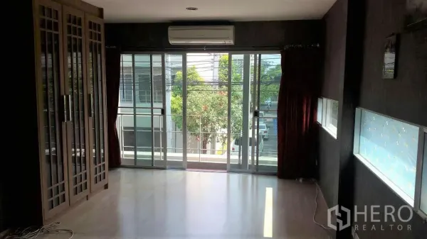 Townhouse for rent in Suan Luang, Bangkok - Spacious living area with sliding glass doors to the balcony and built-in wardrobes.