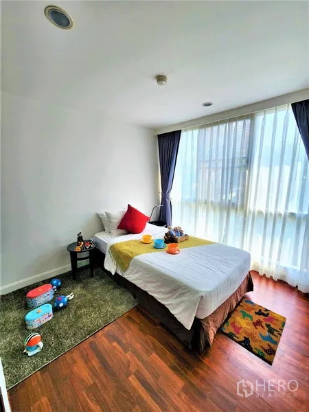 Condominium for rent in Bang Rak, Bangkok - Sunlit single bedroom with floor-to-ceiling curtains and warm wood flooring.
