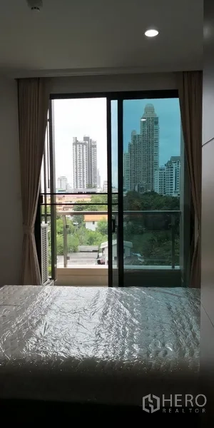 公寓 出租在Sathon, Bangkok - 卧室连接玻璃阳台，眺望城市天际线并配落地窗帘