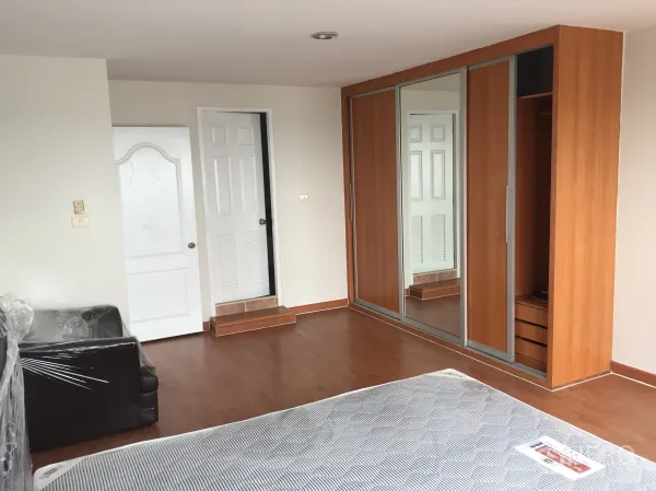Condominium for rent in Khlong Toei, Bangkok - Bedroom view showing large built-in mirrored wardrobe and two white doors.