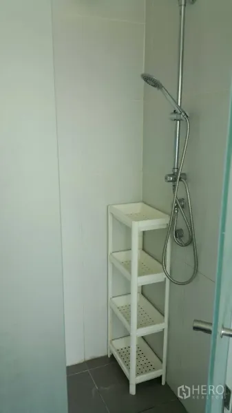 公寓 出租在Watthana, Bangkok - 淋浴间配手持花洒与白色角落置物架。