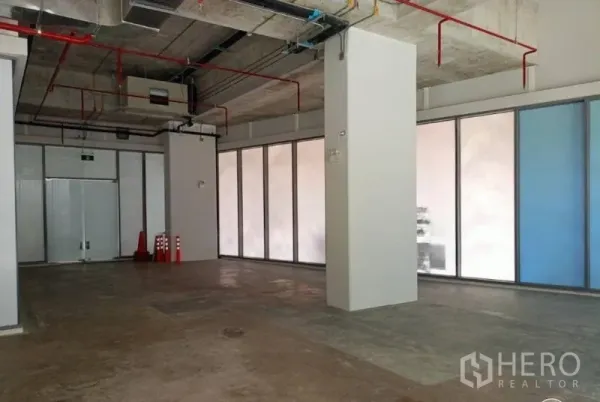 Retail Space for rent in Watthana, Bangkok - Shop interior with support column, emergency exit doors, and full‑height perimeter windows.