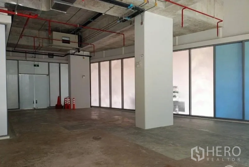 Retail Space for rent in Watthana, Bangkok - Shop interior with support column, emergency exit doors, and full‑height perimeter windows.