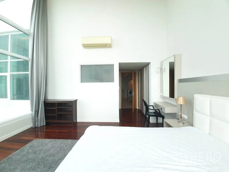 公寓 出租在Ratchathewi, Bangkok - 采光充足的卧室，挑高天花，大窗、白色床头与木地板。