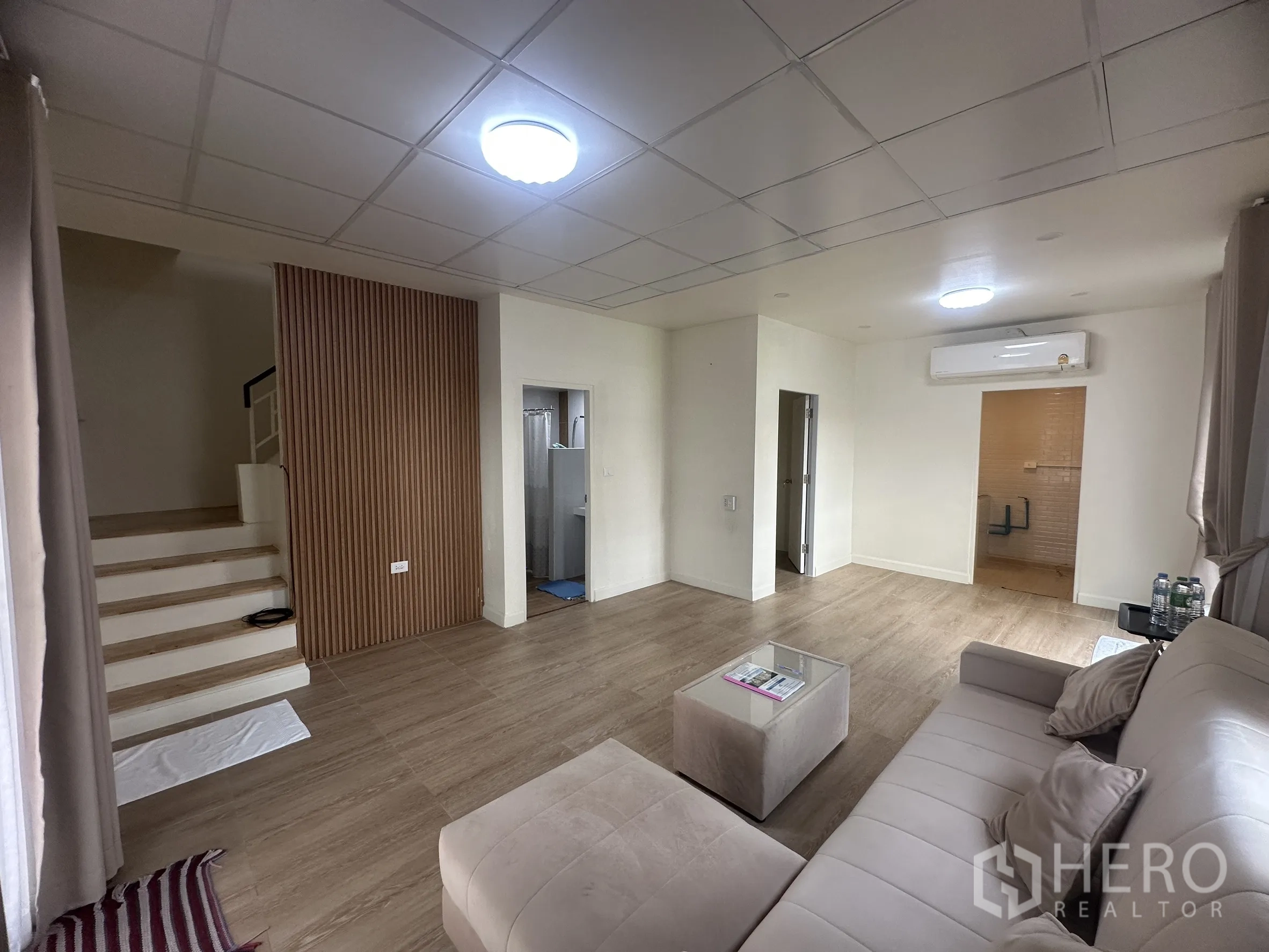 Townhouse for sale in Lam Luk Ka, Pathum Thani - Living area showing the staircase, bathroom entrance, and wall panel feature.