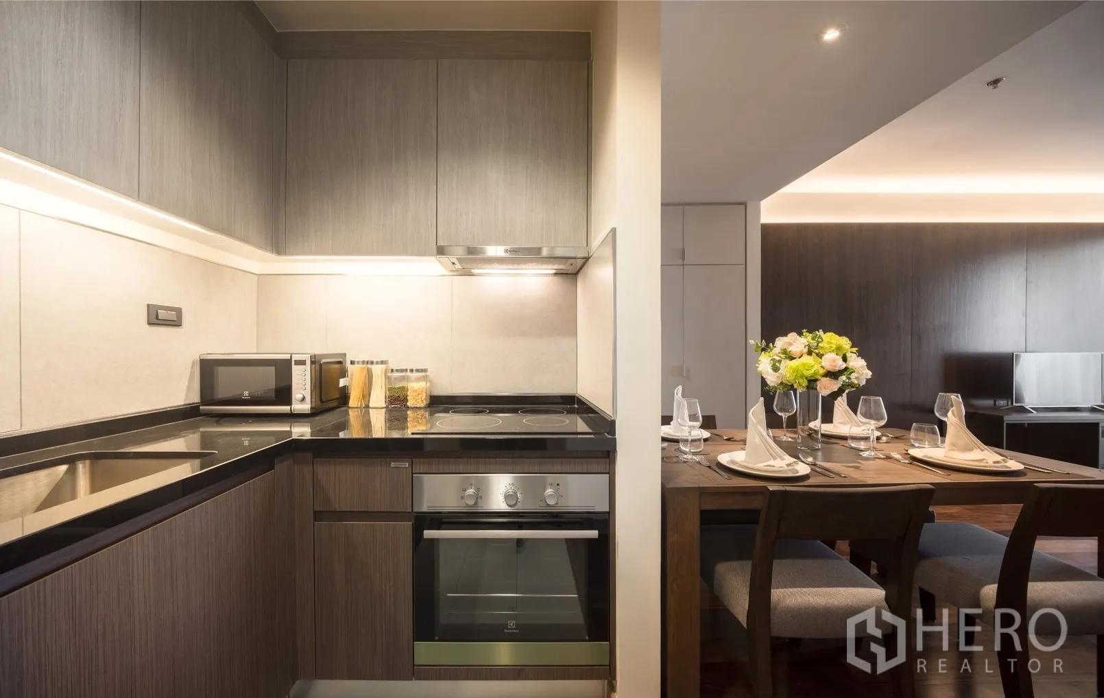 Condominium for rent in Khlong Toei, Bangkok - U-shaped kitchen with cooktop, oven and microwave opening to the dining table.