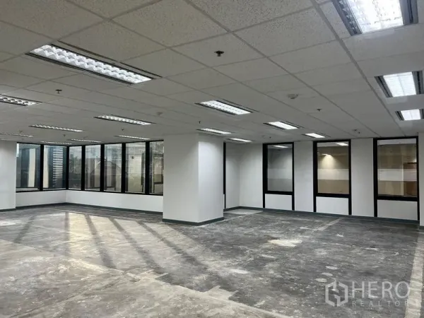 办公空间 出租在Khlong Toei, Bangkok - 开放工位区，荧光灯栅格吊顶，多扇玻璃窗与白色立柱，位于曼谷空堤区。